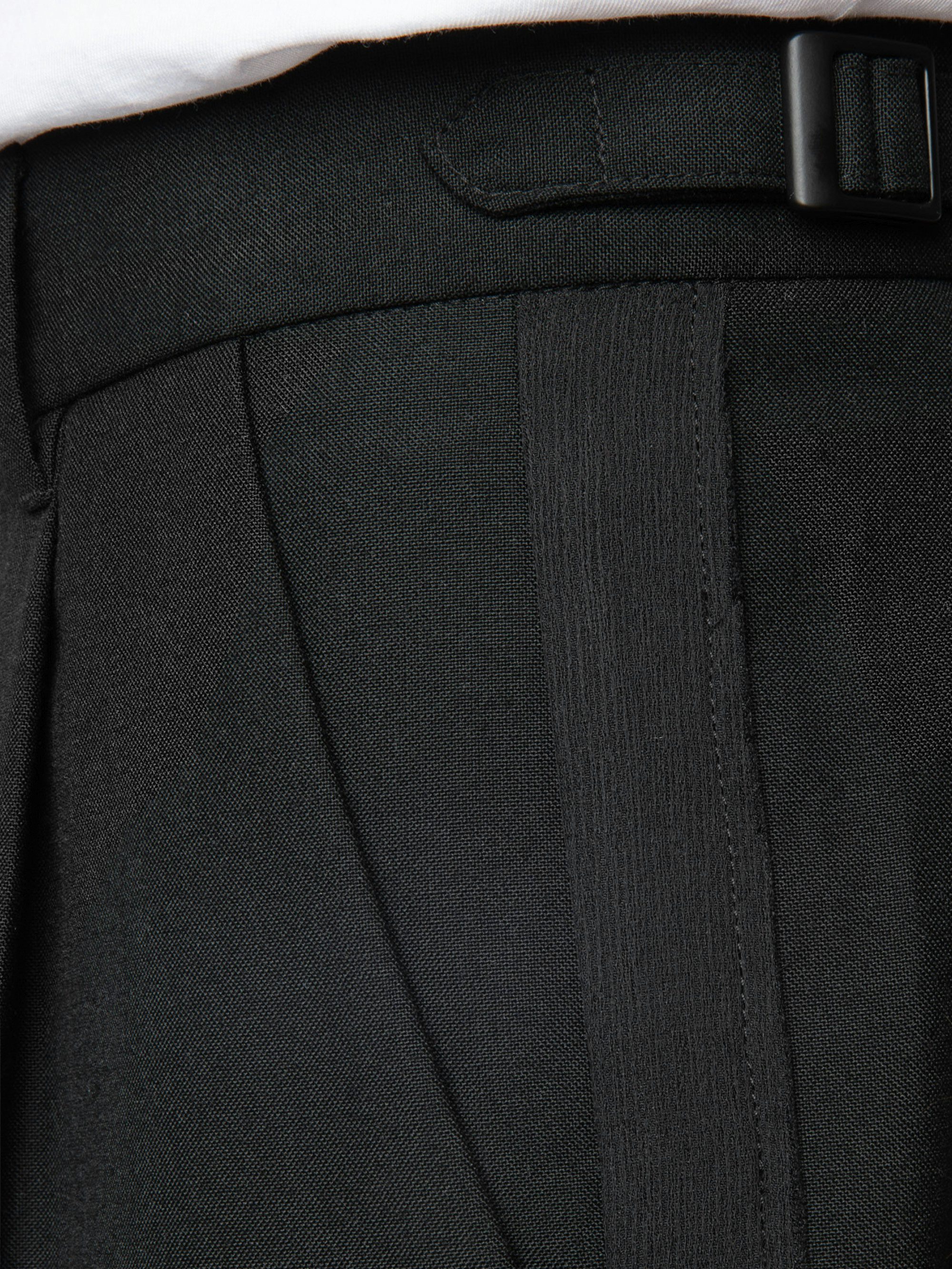 Pawlhose - Schwarze, weite Bundfaltenhose aus Wolle mit Riemen und Studio-Etikett.